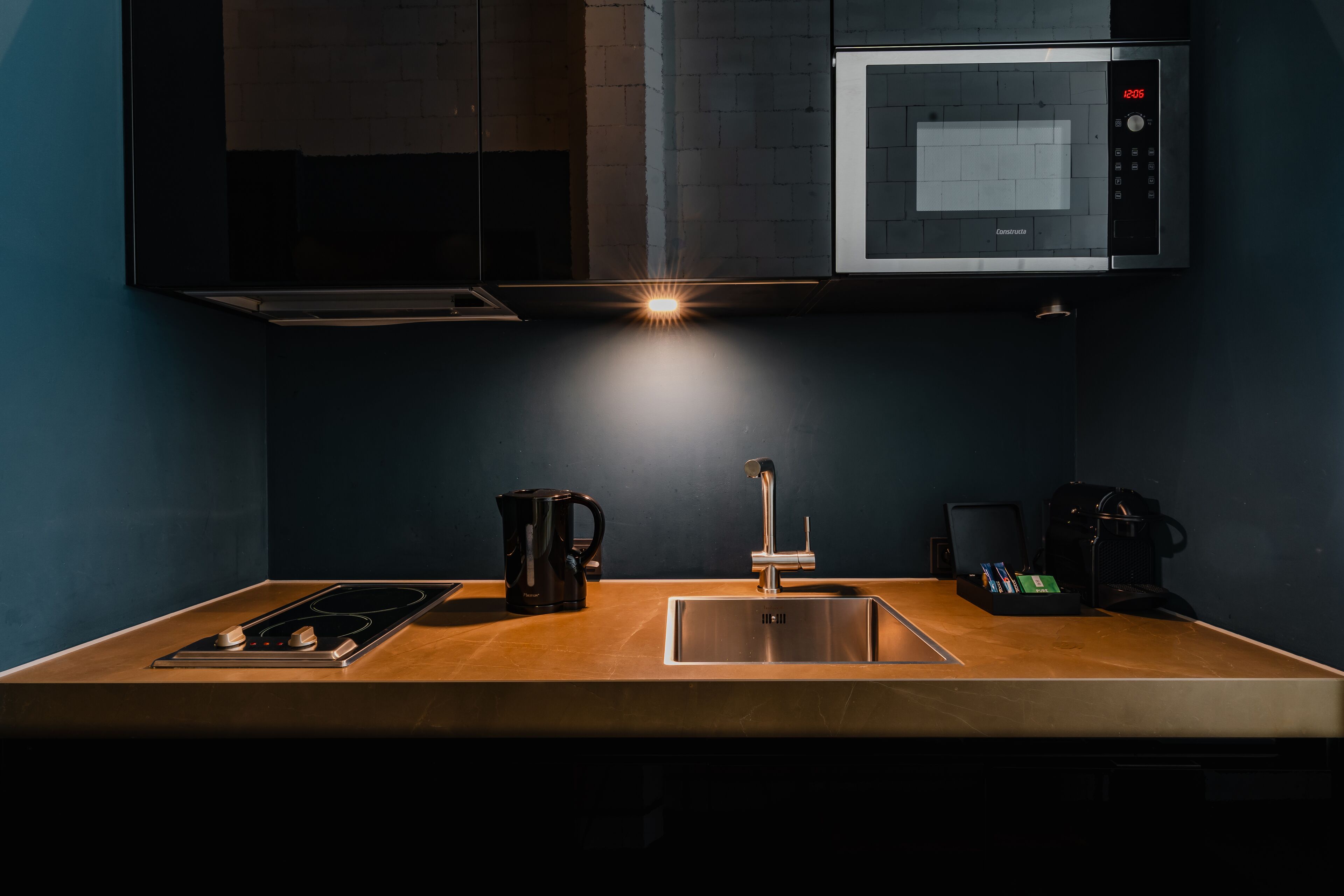 A modern kitchen with a built-in microwave, a stainless steel sink, and a coffee maker.