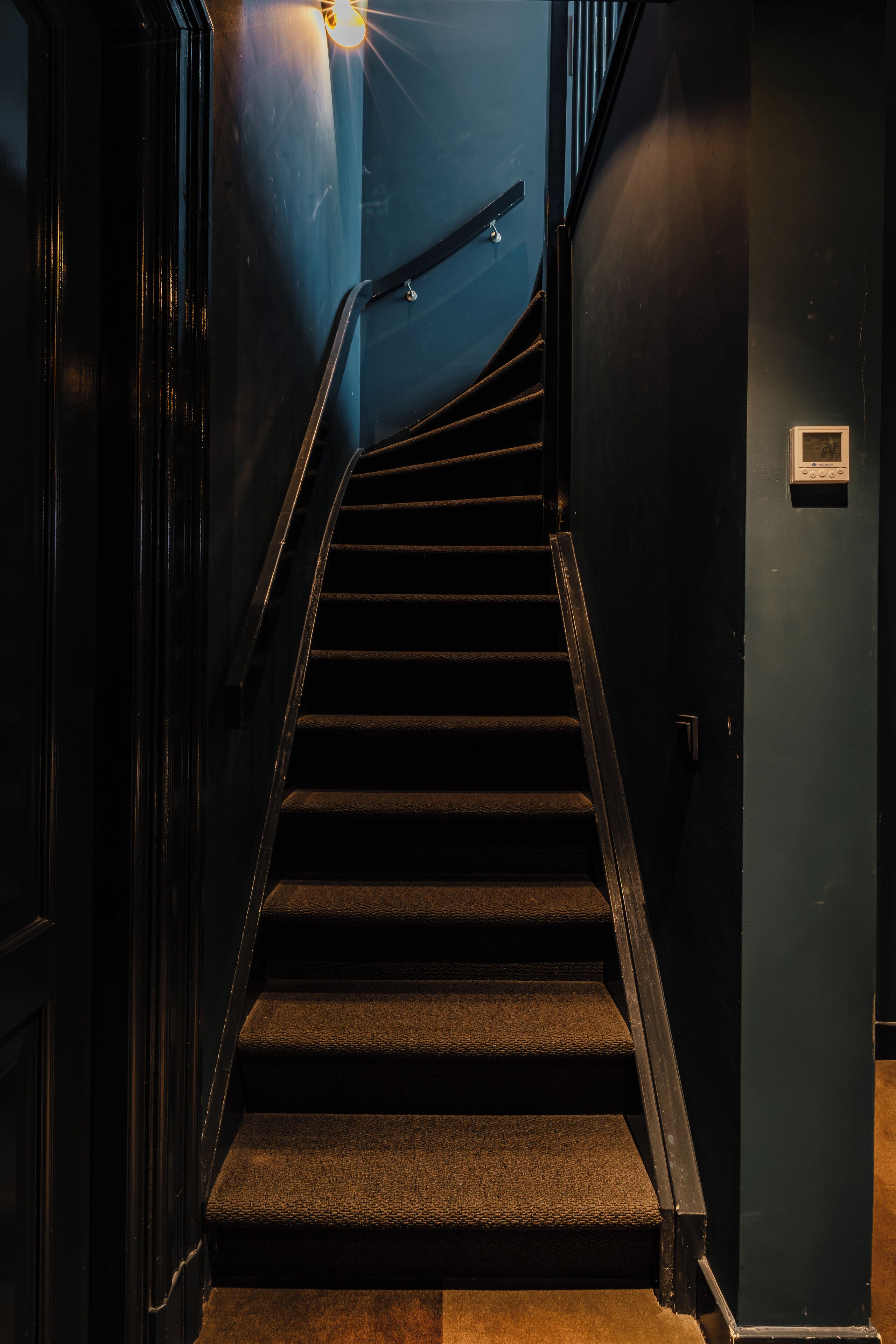 A staircase with a handrail, leading to a landing with a light fixture.