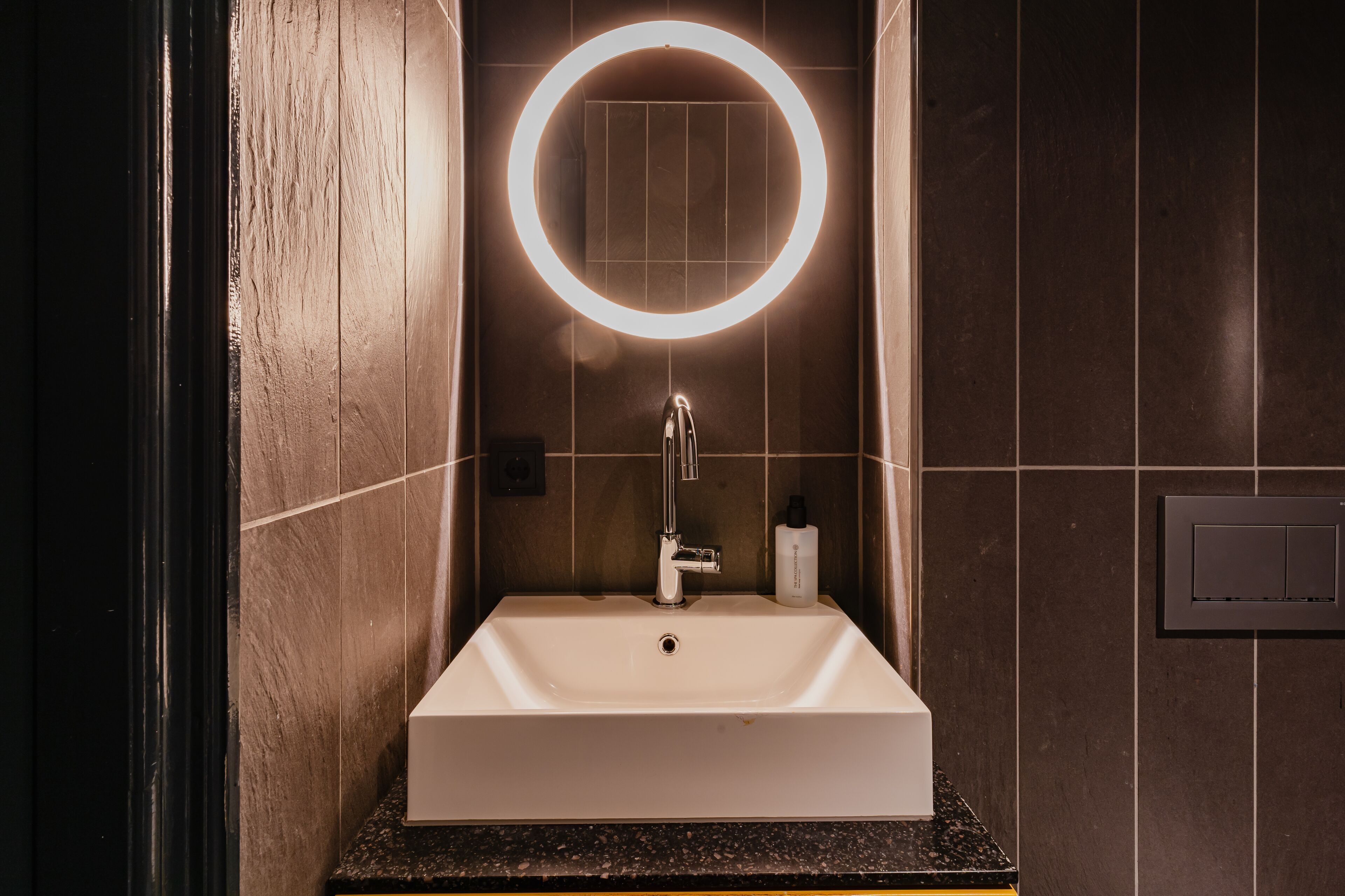 A modern bathroom with a rectangular sink, a round mirror, and a faucet.