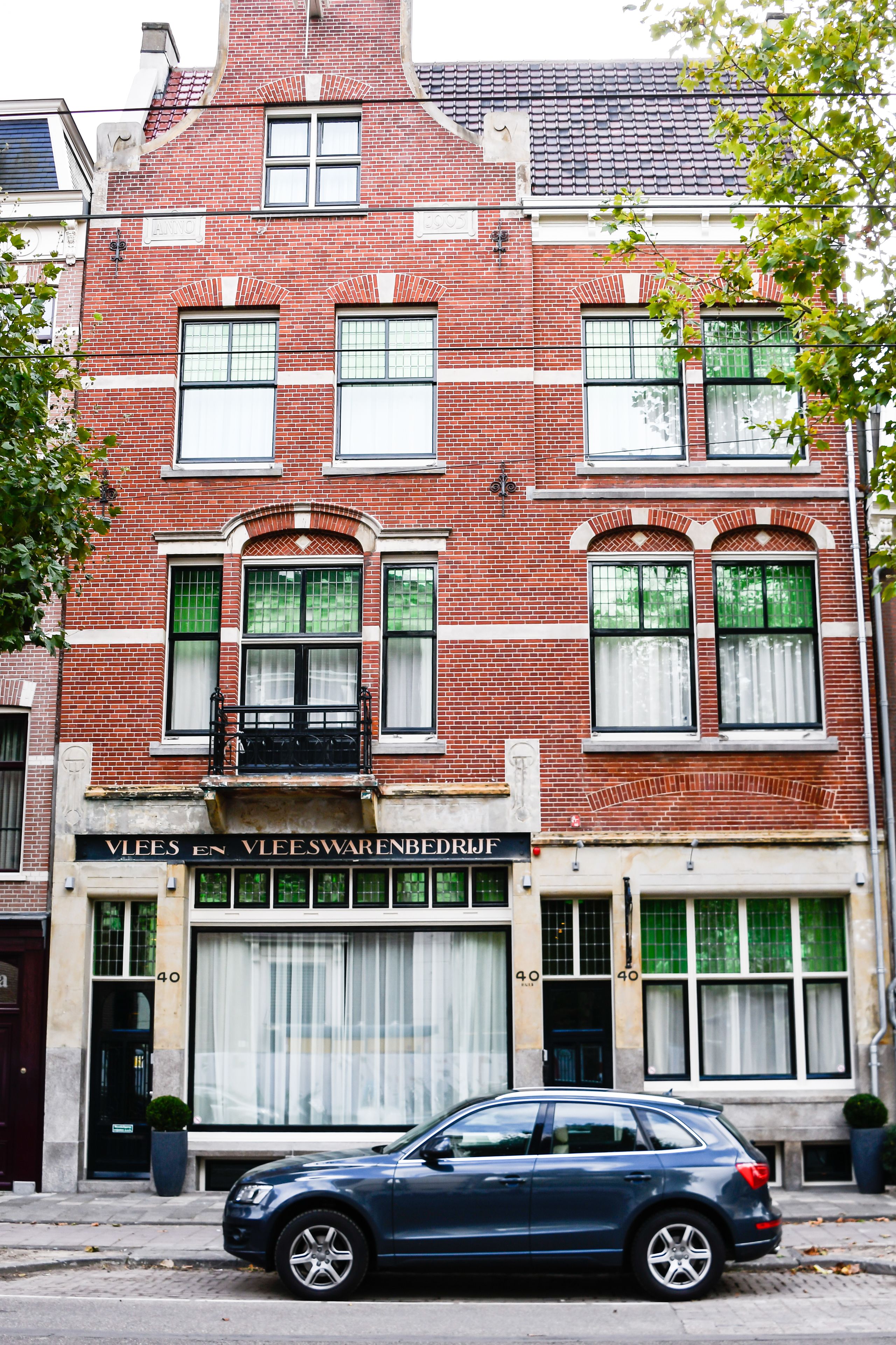 Een rood bakstenen gebouw met een etalage waarop 'Vleeswarenbedrijf' staat.