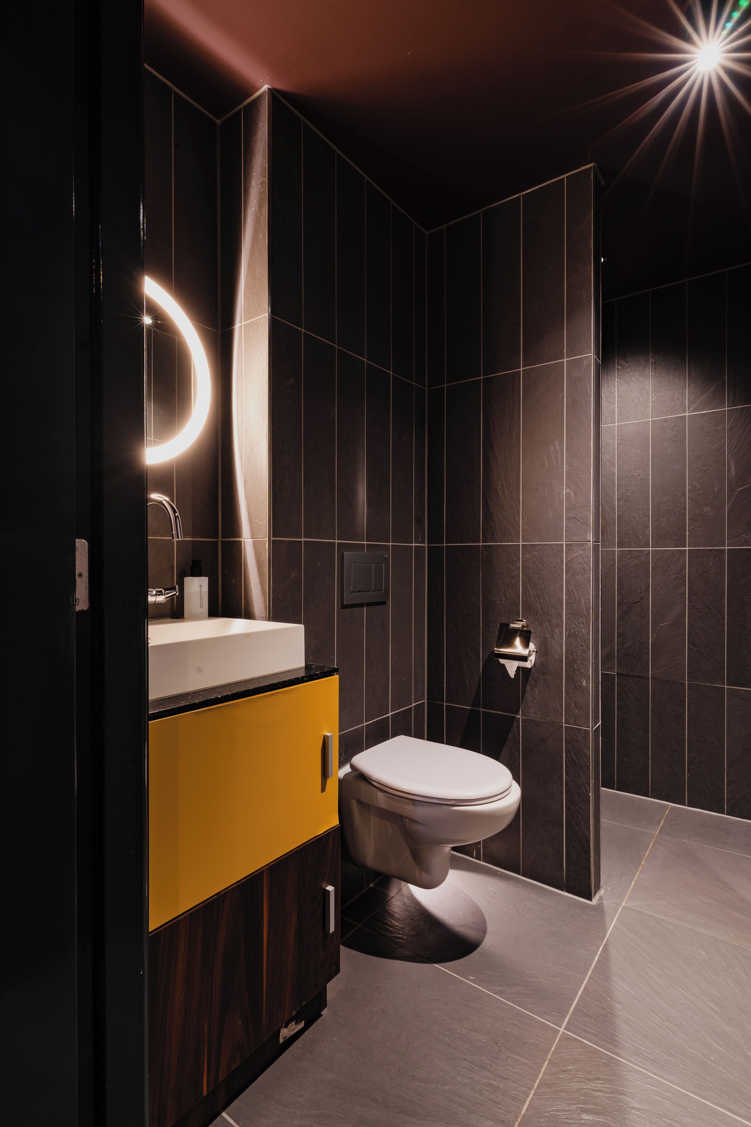 Un baño moderno con inodoro, lavamanos y espejo.