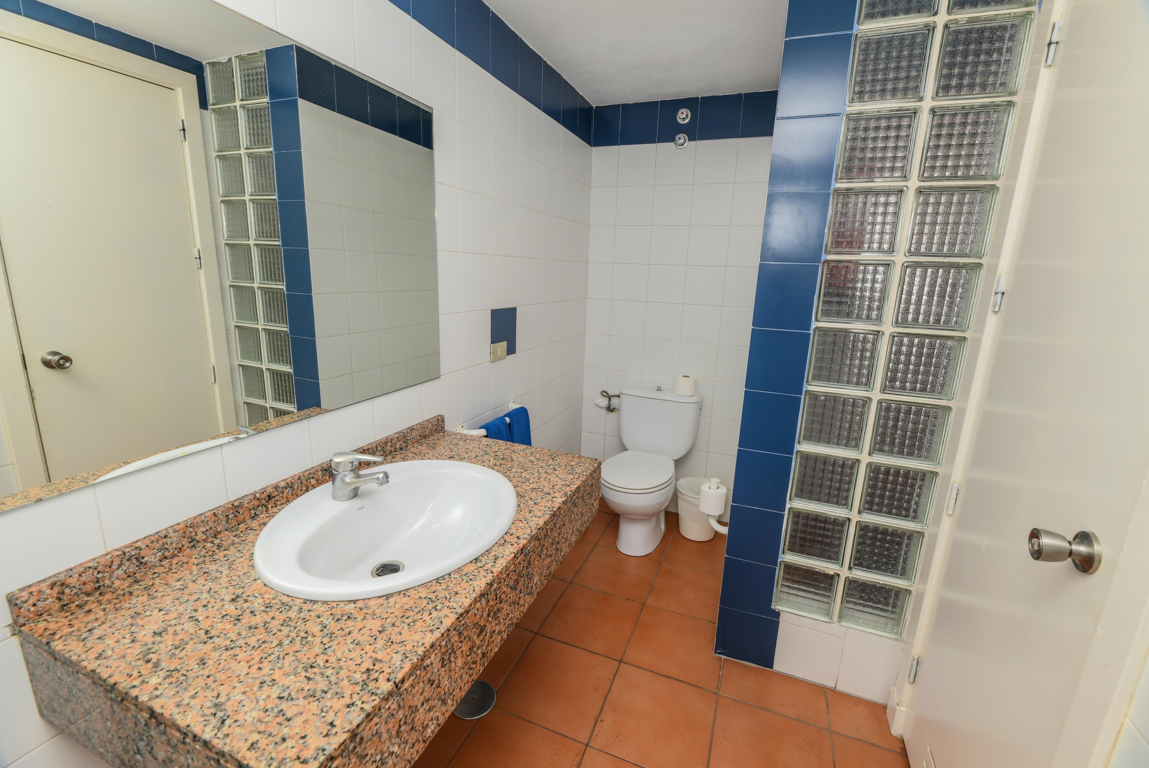 Une salle de bain avec un lavabo blanc, des toilettes et un miroir.