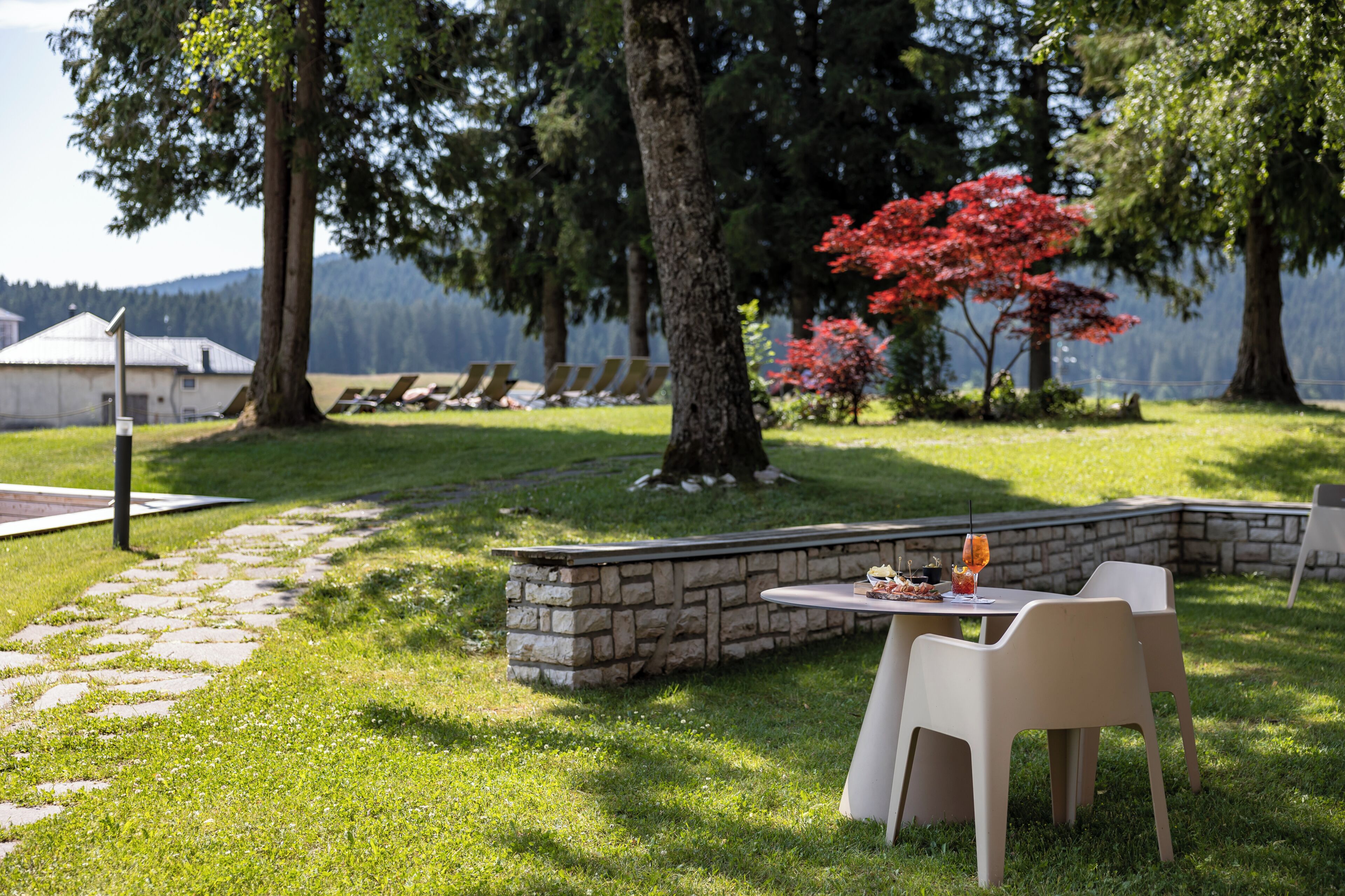 A patio area with stone walls, outdoor seating, and a view of a lake.