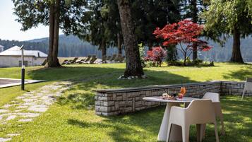A patio area with stone walls, outdoor seating, and a view of a lake.