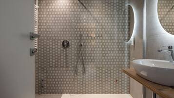 A modern bathroom with a glass shower enclosure, a large mirror, and a white sink on a wooden countertop.