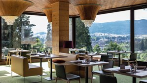 Un restaurante con mesas y sillas, ventanas amplias y vistas al paisaje.