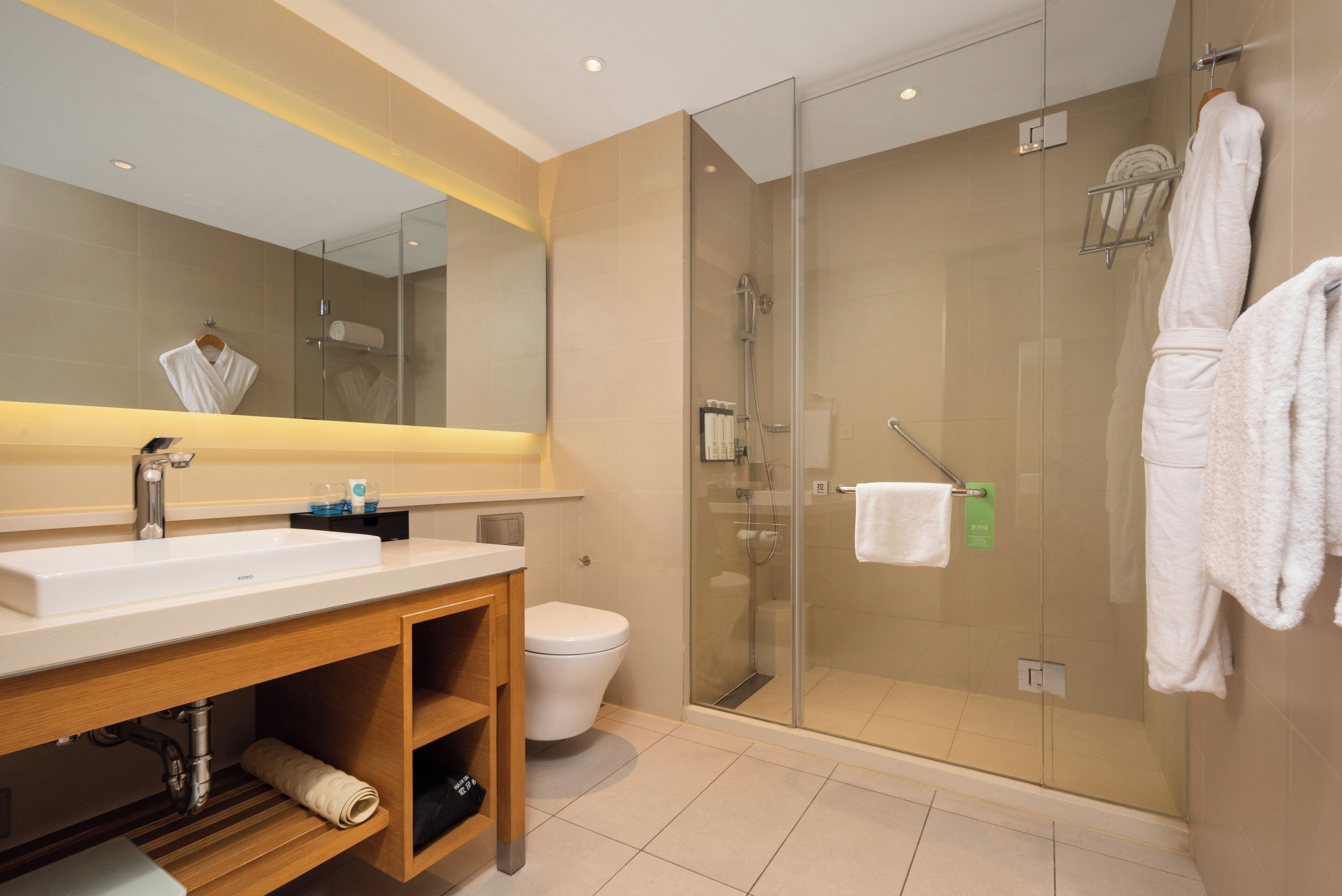 A modern bathroom with a glass-enclosed shower, a white sink, and a wooden vanity.