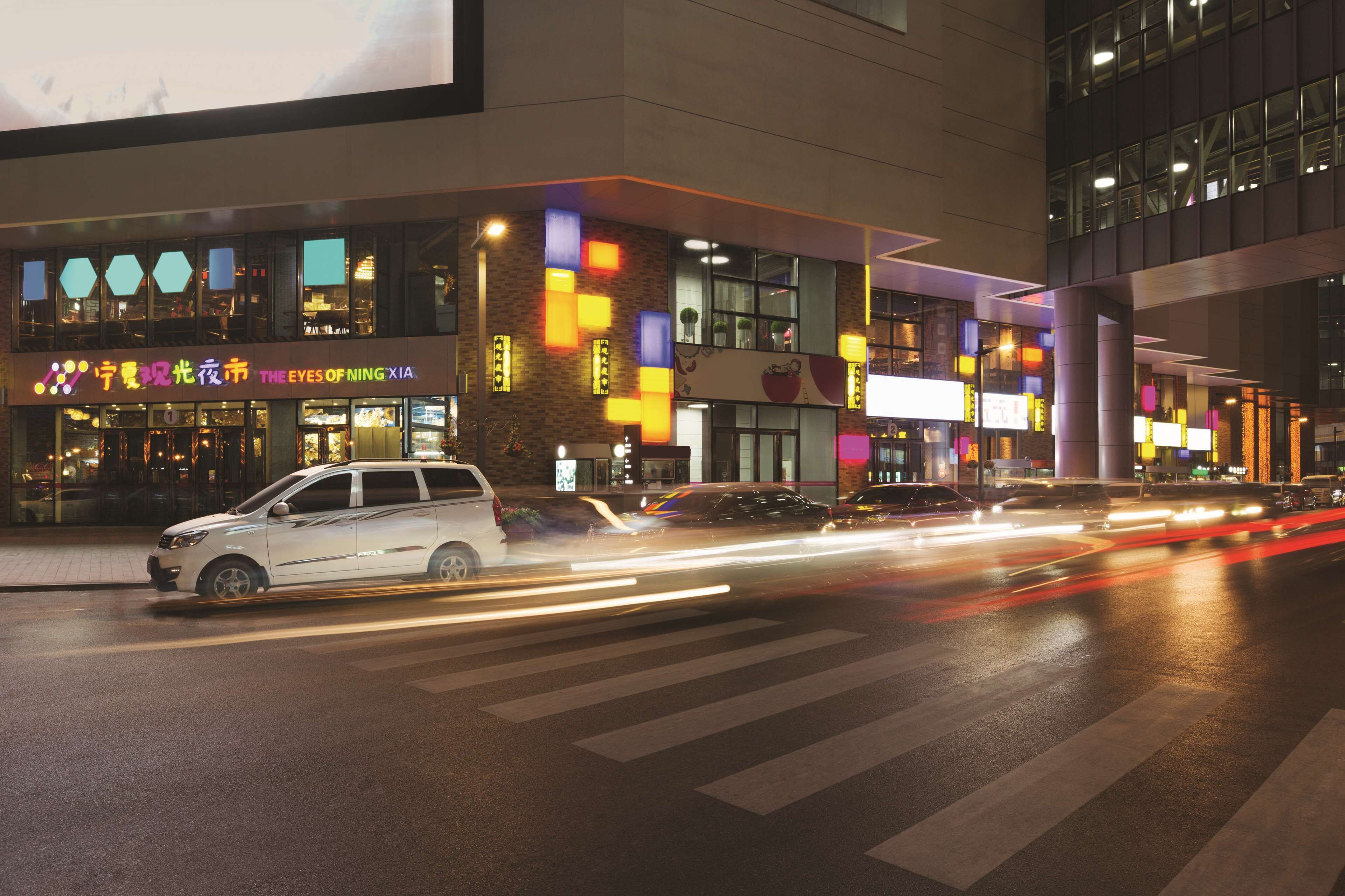 A modern building with illuminated signage and a crosswalk.