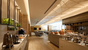 Una àmplia zona de buffet amb nombroses estacions de servei, una llarga barra i una zona de seients amb taules i cadires.