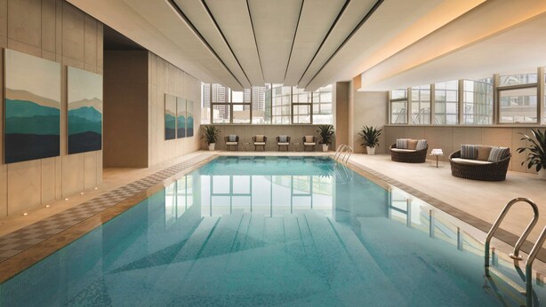 Una piscina interior amb una vista despejada de l'horitzó urbà a través de grans finestres.