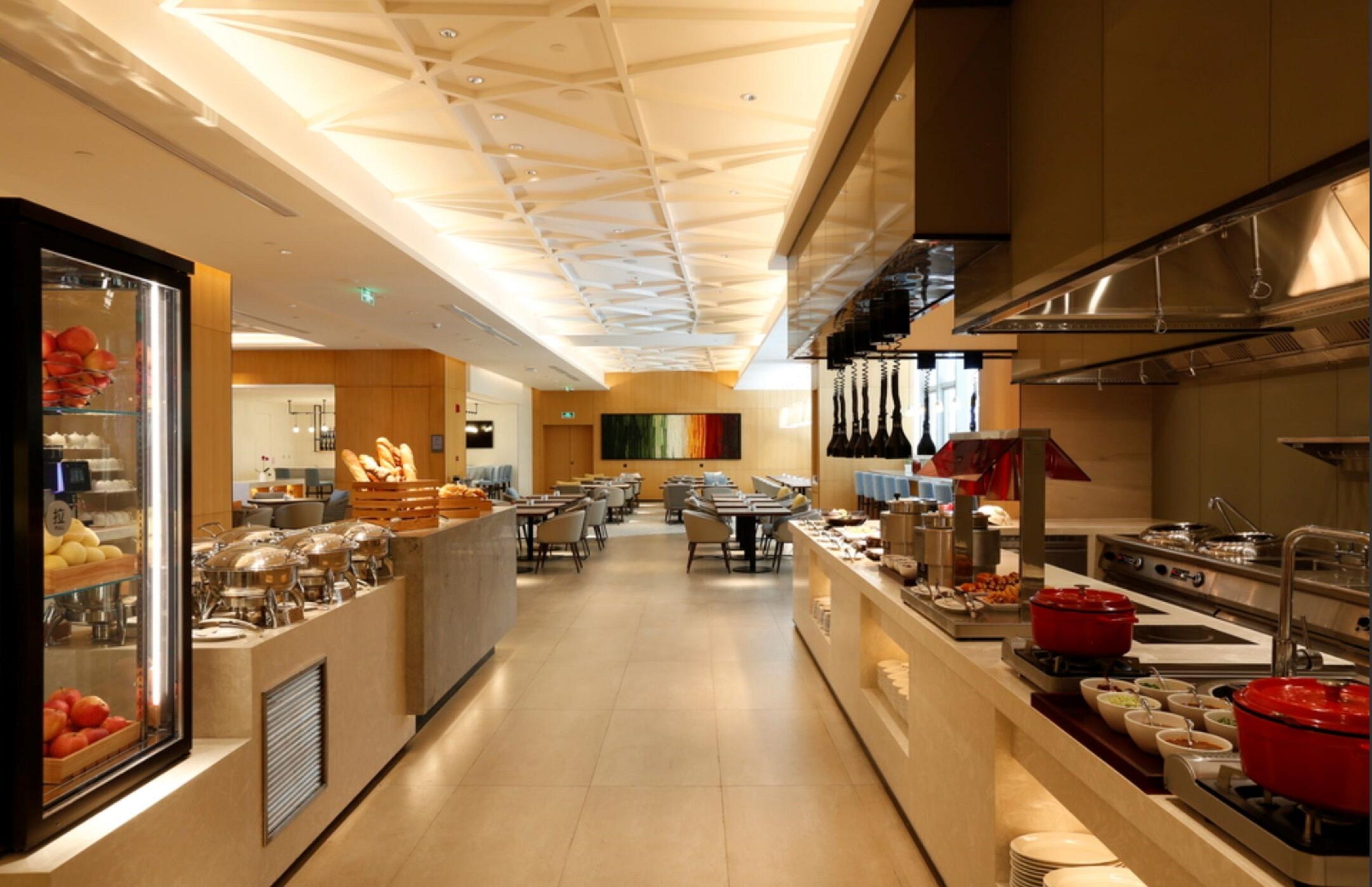 Une cuisine d’hôtel moderne dotée d’un îlot central, d’un espace buffet et de places assises pour les clients.