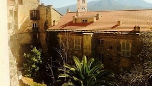 Un edificio histórico con una torre de campanas, muros de piedra y techo de tejas rojas.