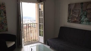 Una sala de estar con una mesa de centro de vidrio, un sofá oscuro y una puerta que da a un balcón.