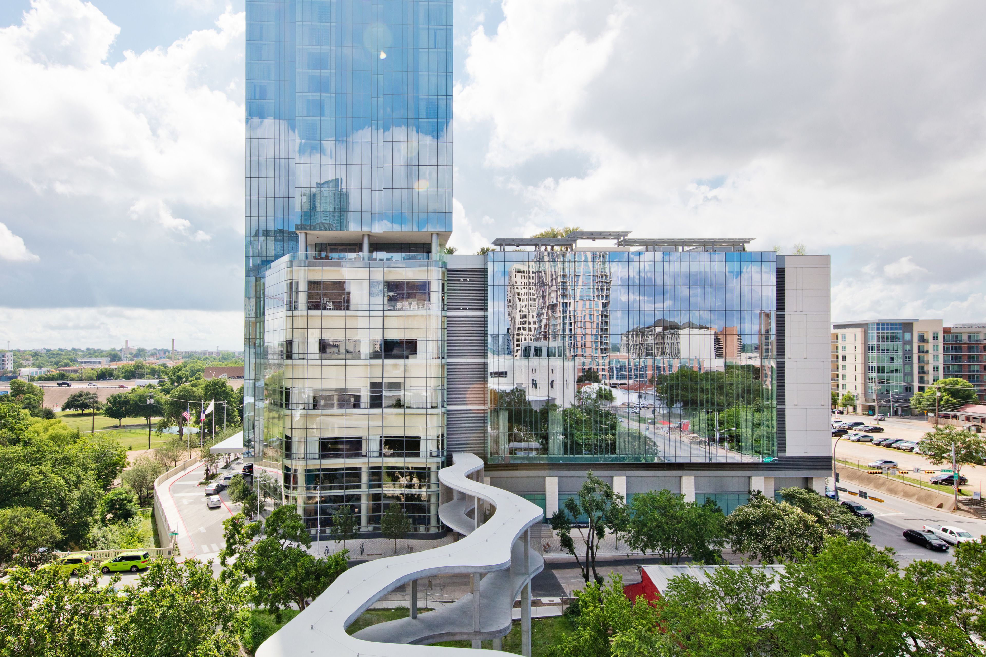 A modern building with a glass facade and a curved structure in front.