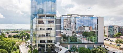 A modern building with a glass facade and a curved structure in front.