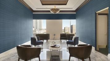 A modern lounge area with a large window, two sofas, a coffee table, and a decorative chandelier.