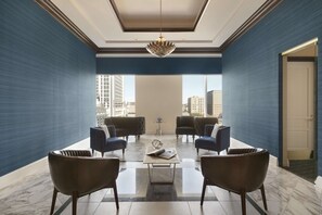 A modern lounge area with a large window, two sofas, a coffee table, and a decorative chandelier.
