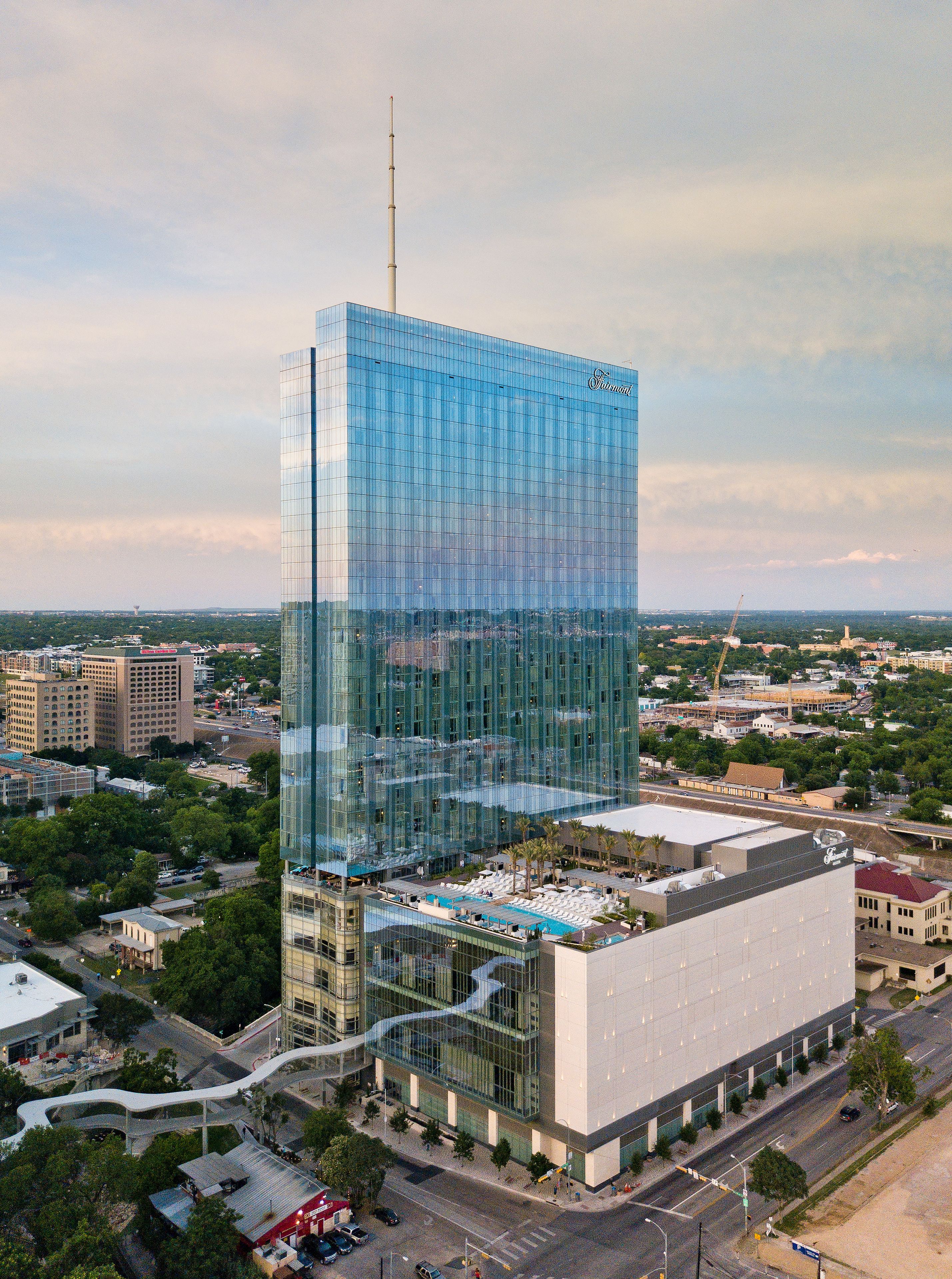 A modern glass skyscraper with a rooftop pool area.