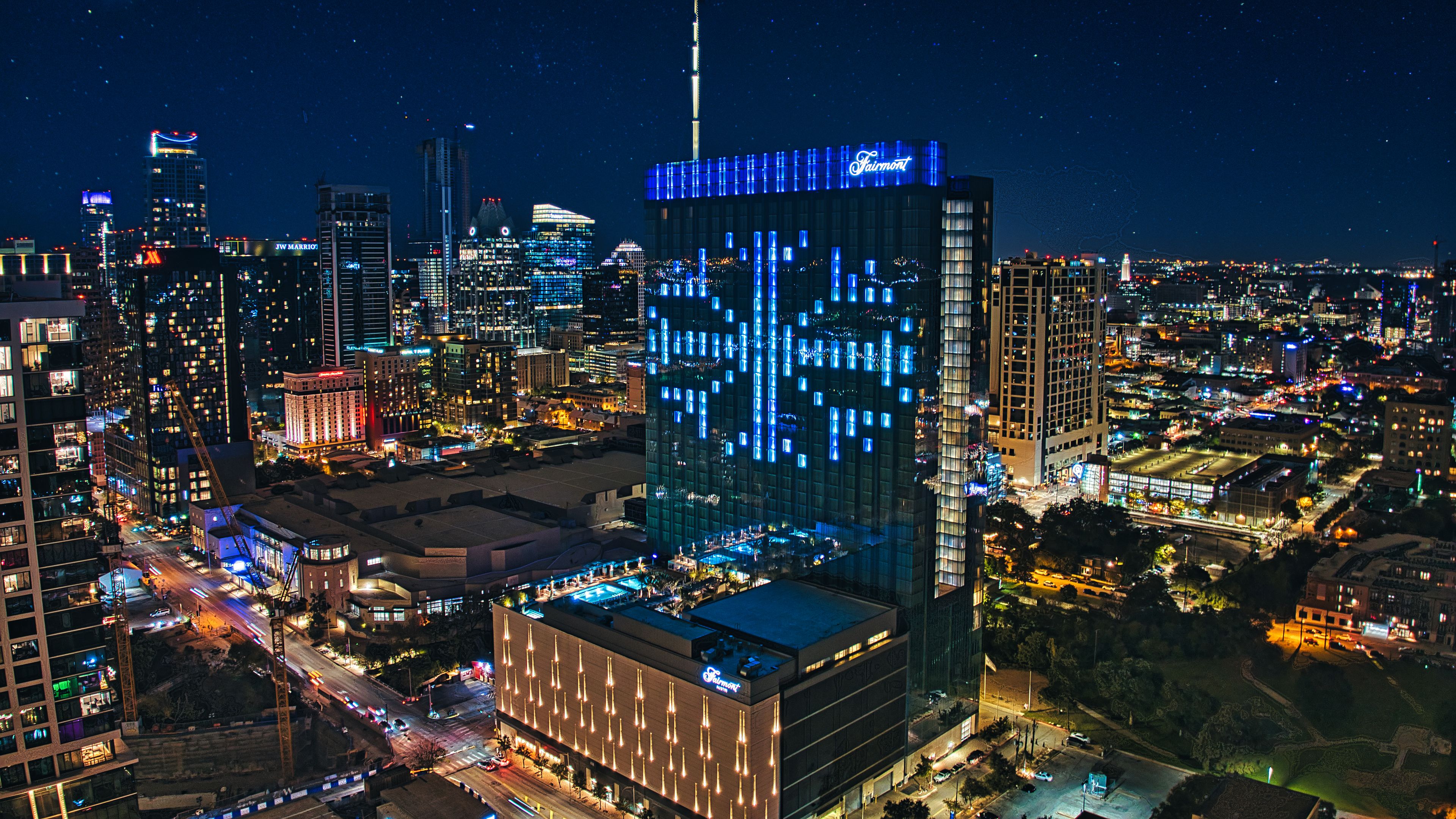 Un hotel de gran altura con una fachada iluminada distintiva, rodeado por un paisaje urbano nocturno.