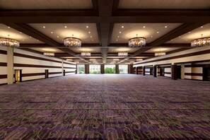 A large, well-lit conference room with patterned carpet, chandeliers, and large windows.