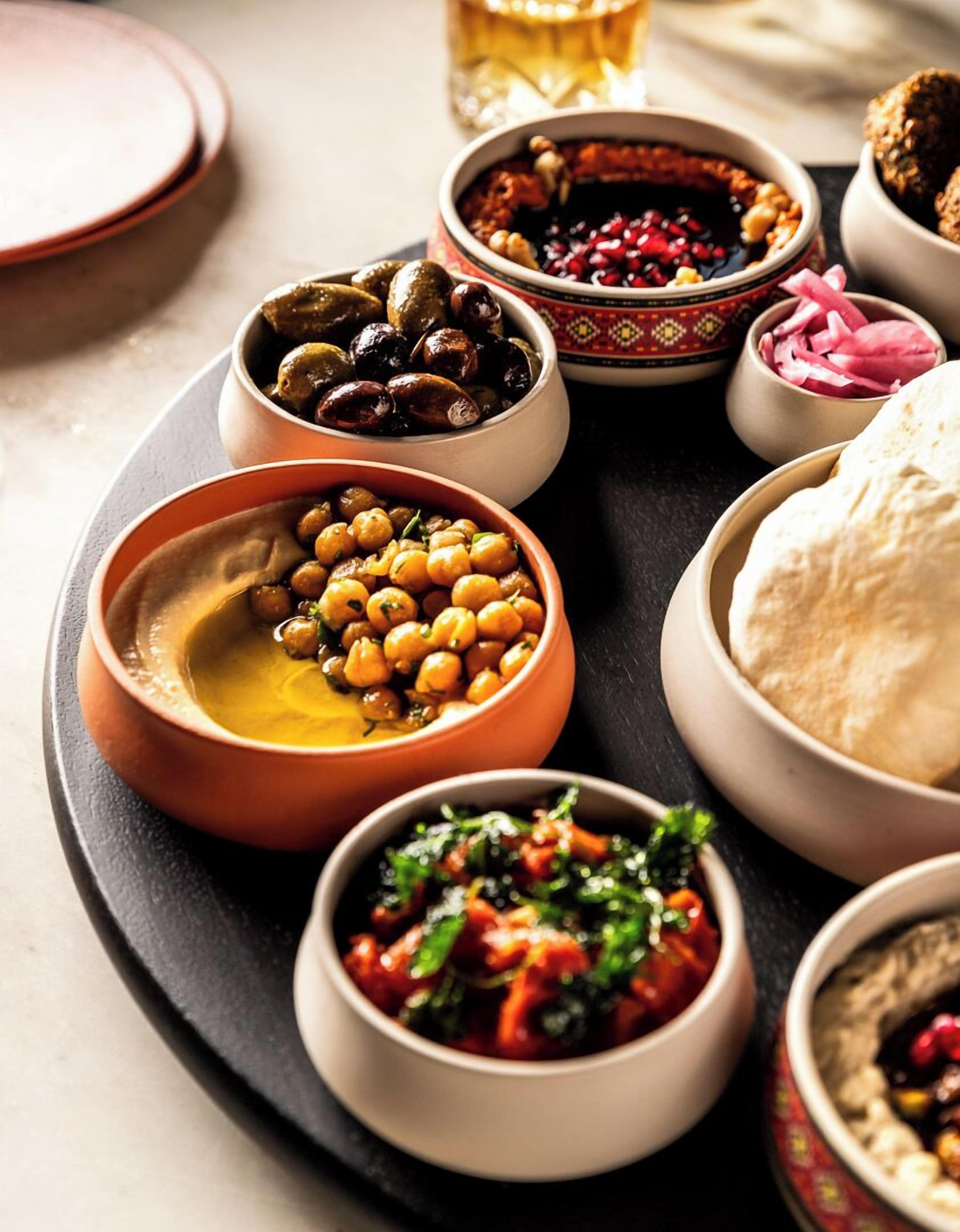 A variety of dishes including olives, chickpeas, and a bowl of what appears to be a tomato-based dish, served on a tray.