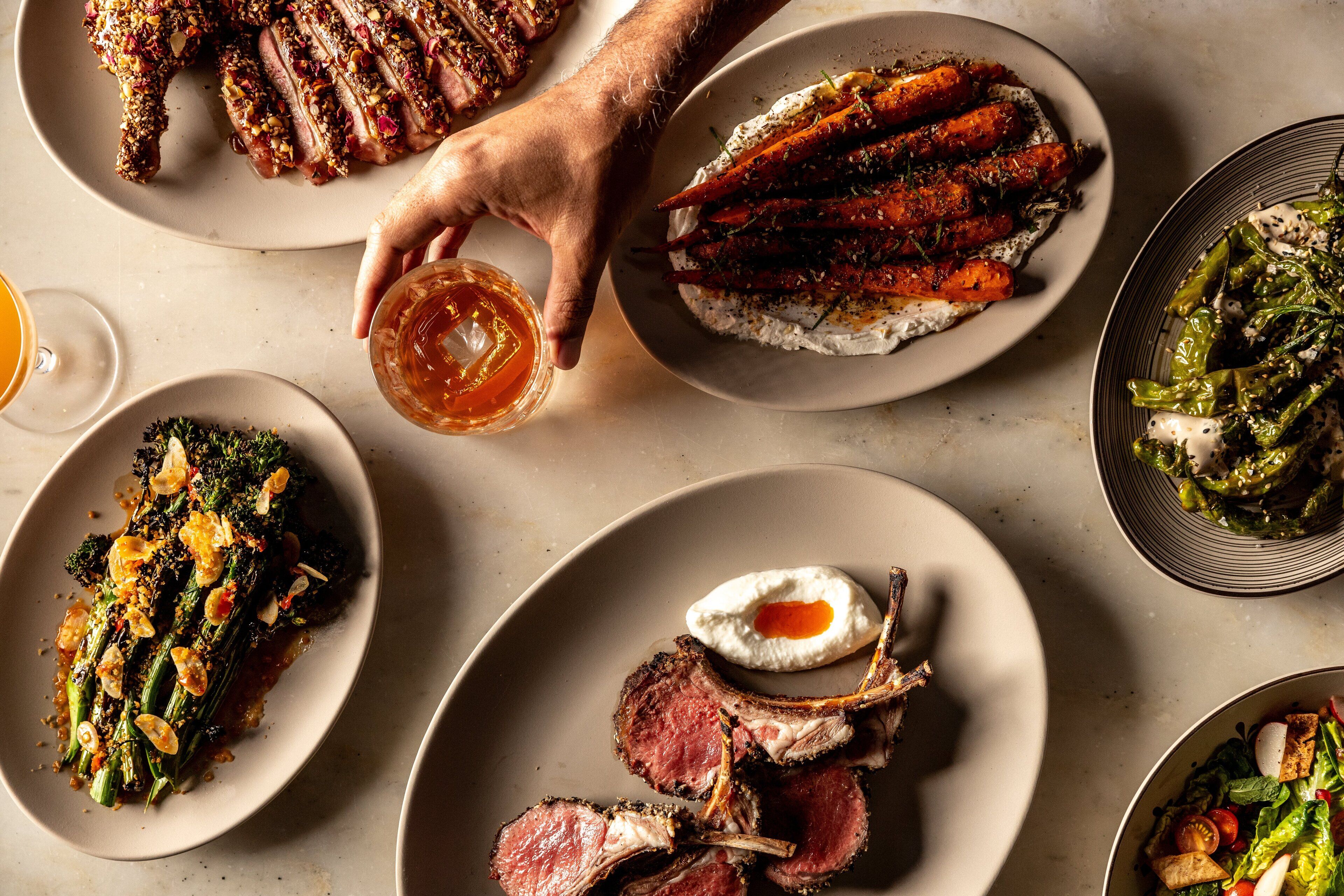 A variety of dishes including roasted meats, vegetables, and a glass of beer on a dining table.