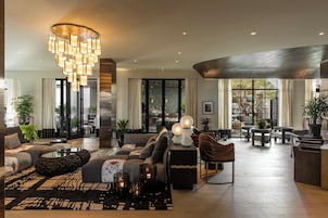A spacious living area with a modern chandelier, comfortable seating, and a view through large windows.