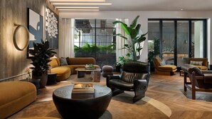 A modern living room with a sofa, armchairs, a coffee table, and a large plant.