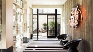A modern interior with a black and white striped floor, a glass door entrance, and a wall-mounted abstract art piece.