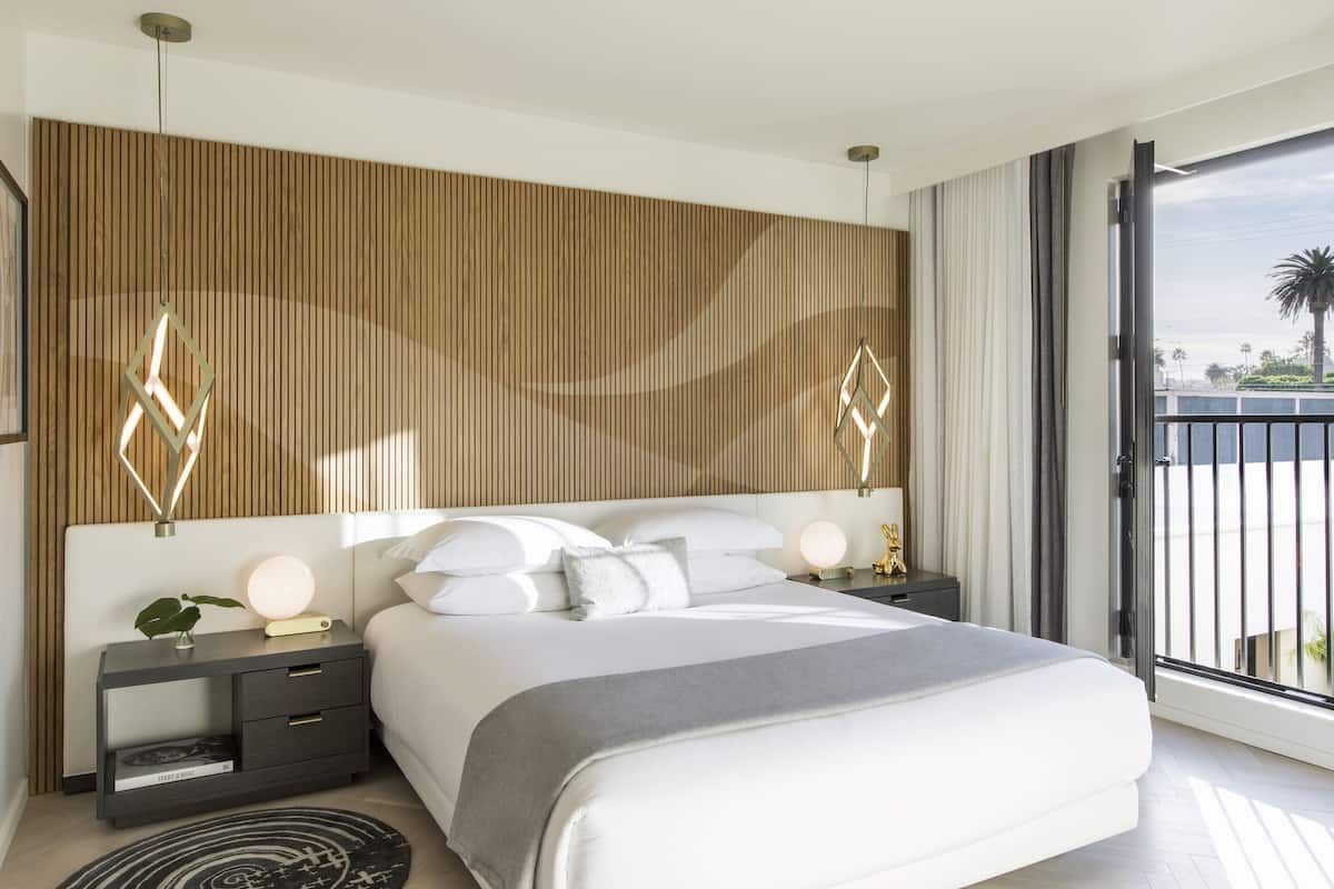 Ein modernes Schlafzimmer mit einem großen Bett, einer Wand aus Holzpaneelen und einem Balkon mit Blick.