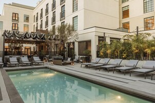Una piscina al aire libre, sombrillas, sillones reclinables de piscina