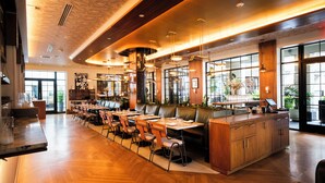 A modern restaurant with wooden flooring, leather booths, and pendant lighting.