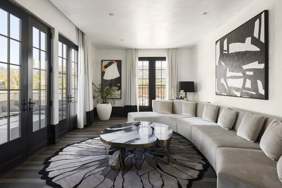 A modern living room with a large sectional sofa, a round coffee table, and a large abstract painting on the wall.