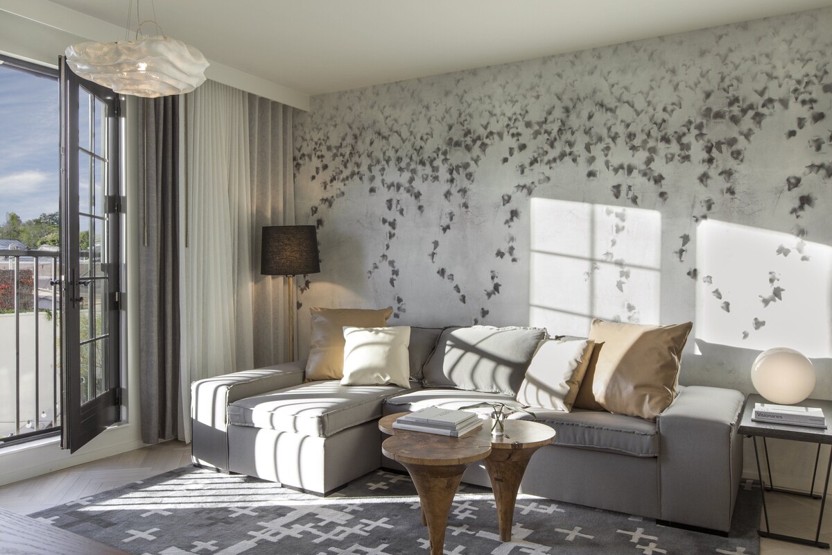 A modern living room with a sectional sofa, a coffee table, and a large window with curtains.