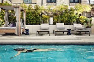 Una piscina al aire libre, sombrillas, sillones reclinables de piscina