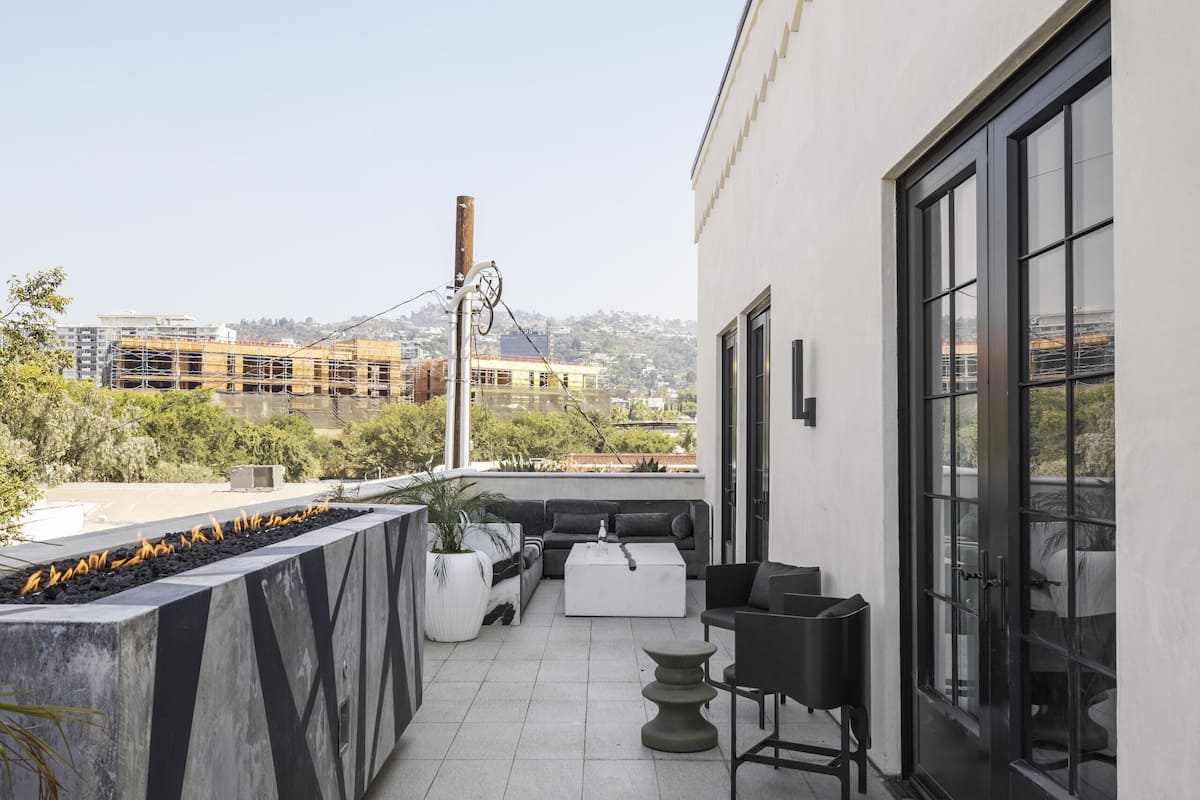 Eine Dachterrasse mit modernem Design, ausgestattet mit einer Sitzecke, die eine Couch und Stühle, einen kleinen Tisch und einen dekorativen Pflanzkasten umfasst.