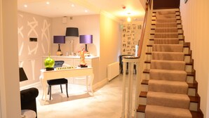 A modern interior with a staircase, a dining area with a white table and chairs, and a kitchen with a purple lamp. - The Lawrence (Athboy)