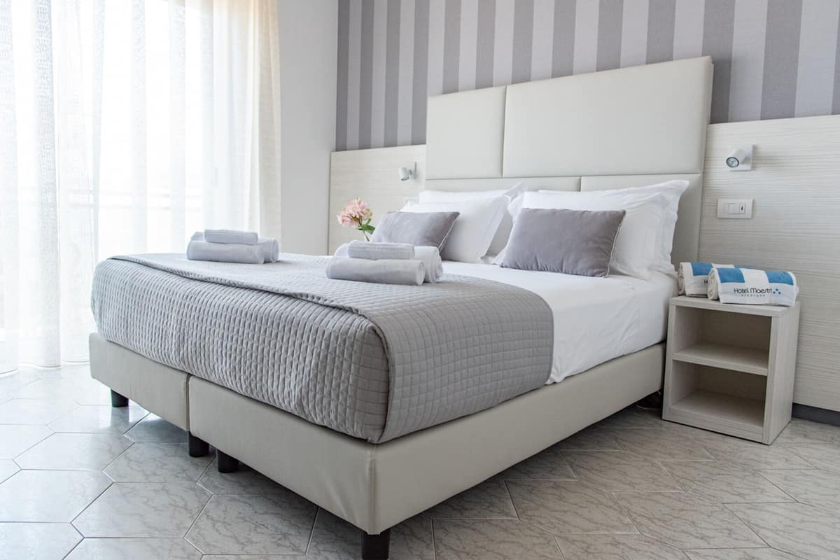 A modern hotel room with a large bed, a bedside table, and a nightstand.