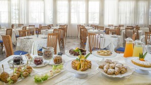 A banquet hall with tables set for a meal, featuring a variety of desserts and beverages. - Hotel Maestri (Riccione)