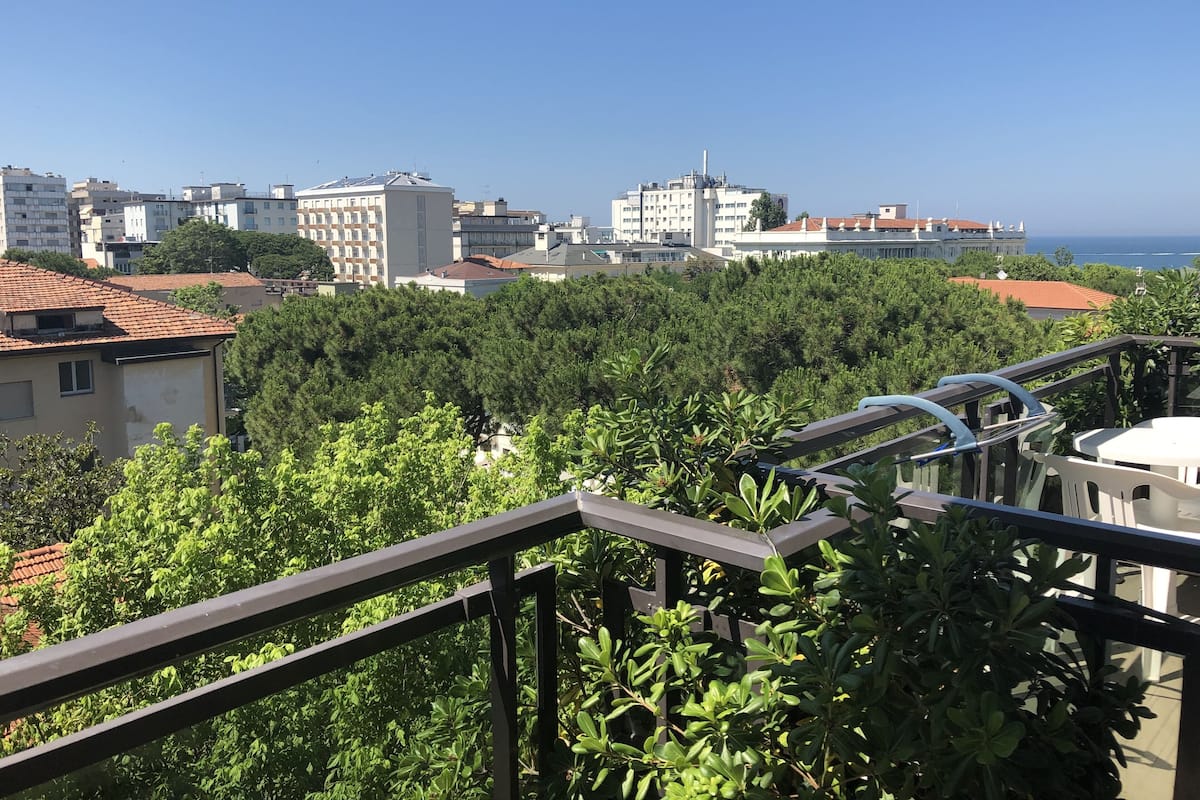 A balcony with a view of a cityscape and the sea.
