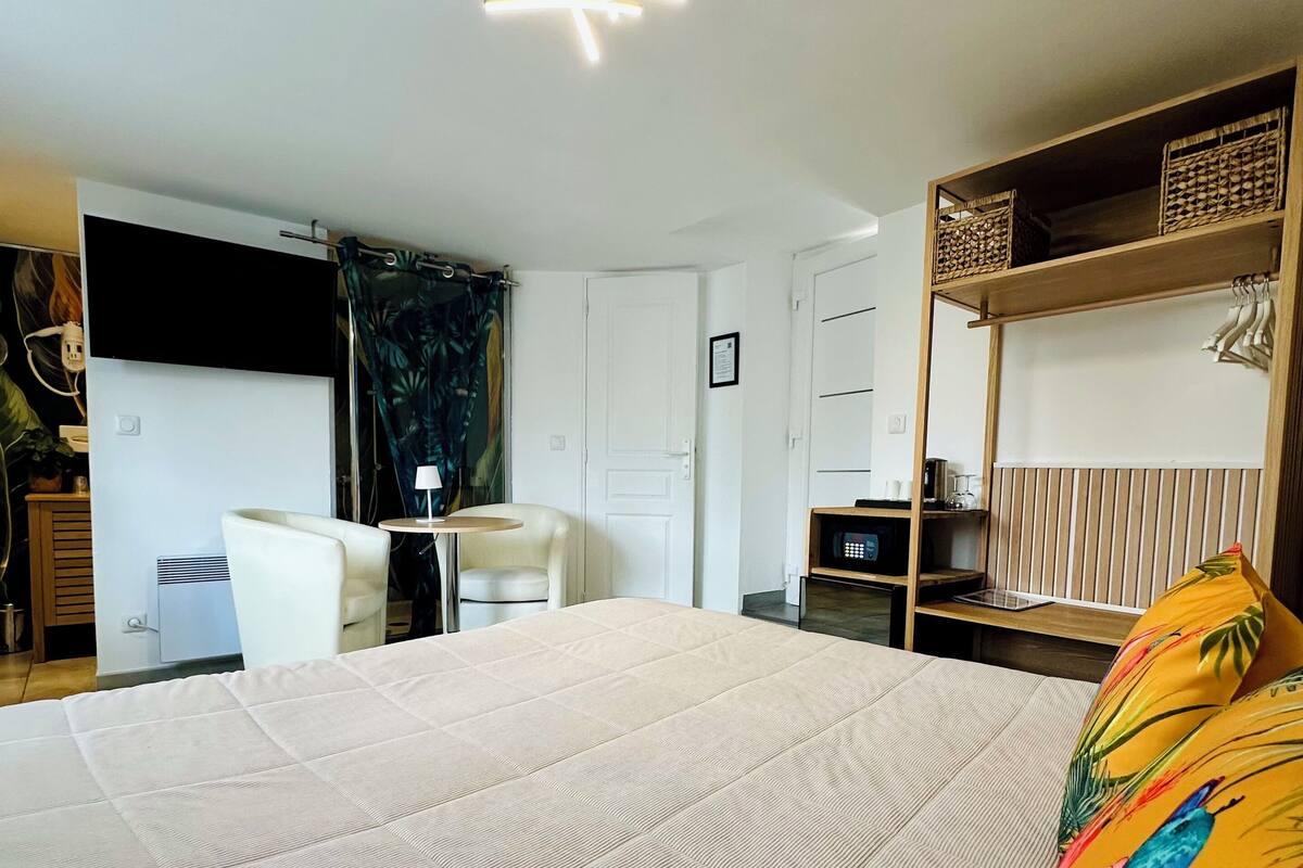 A hotel room with a large bed, a desk, a chair, a wardrobe, and a ceiling light fixture.
