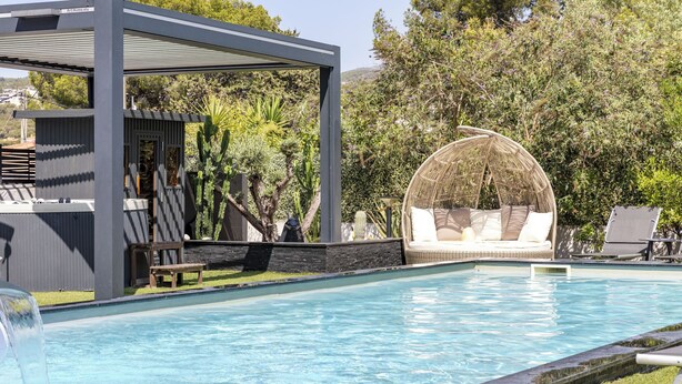A swimming pool with a covered seating area and a lounge chair. - Hotel Eden Cassis (Cassis)