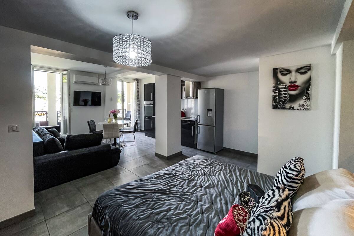 A modern living room with a large bed, a sofa, and a dining area.