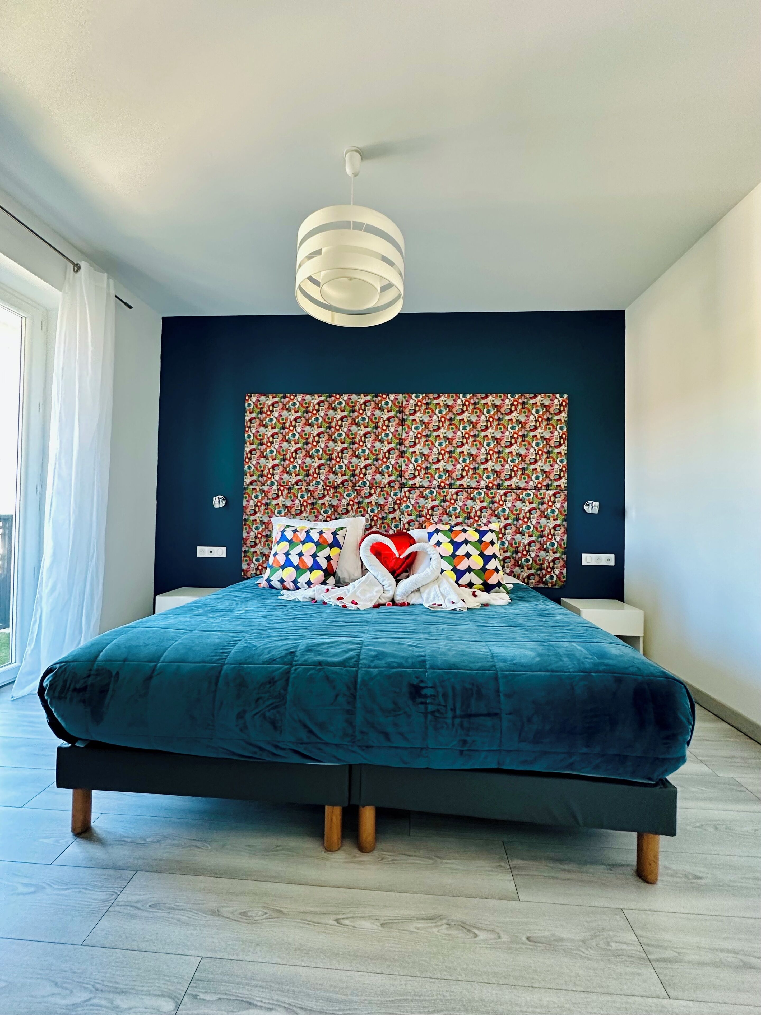 Un dormitorio moderno con una cama grande, un cabecero decorativo y vistas al exterior.