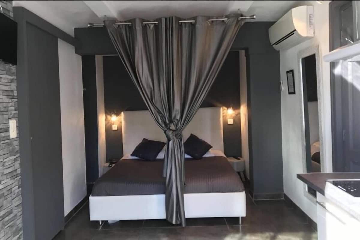 A modern bedroom with a bed, bedside tables, and a curtain.