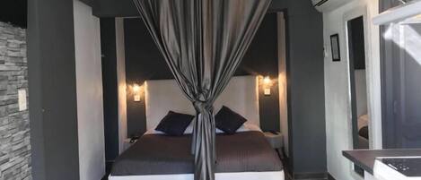 A modern bedroom with a bed, bedside tables, and a curtain.