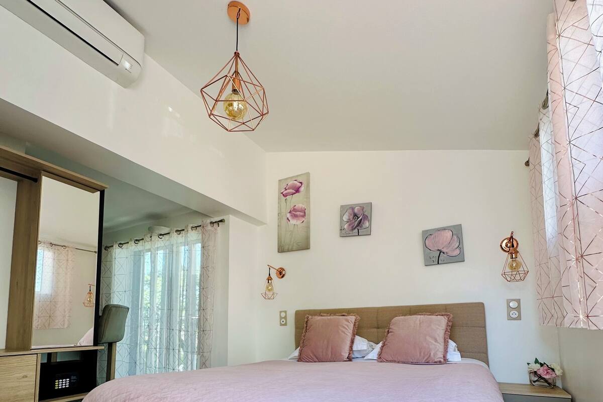 A bedroom with a bed, bedside tables, a mirror, and wall art.