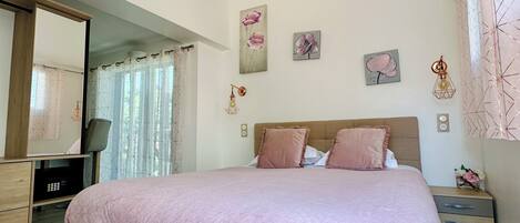 A bedroom with a bed, bedside tables, a mirror, and wall art.