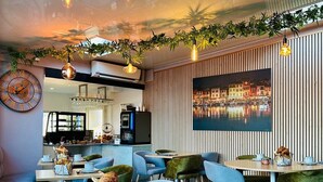 A modern restaurant with a high ceiling, exposed ductwork, and a view of the cityscape through a skylight. - Hotel Eden Cassis (Cassis)