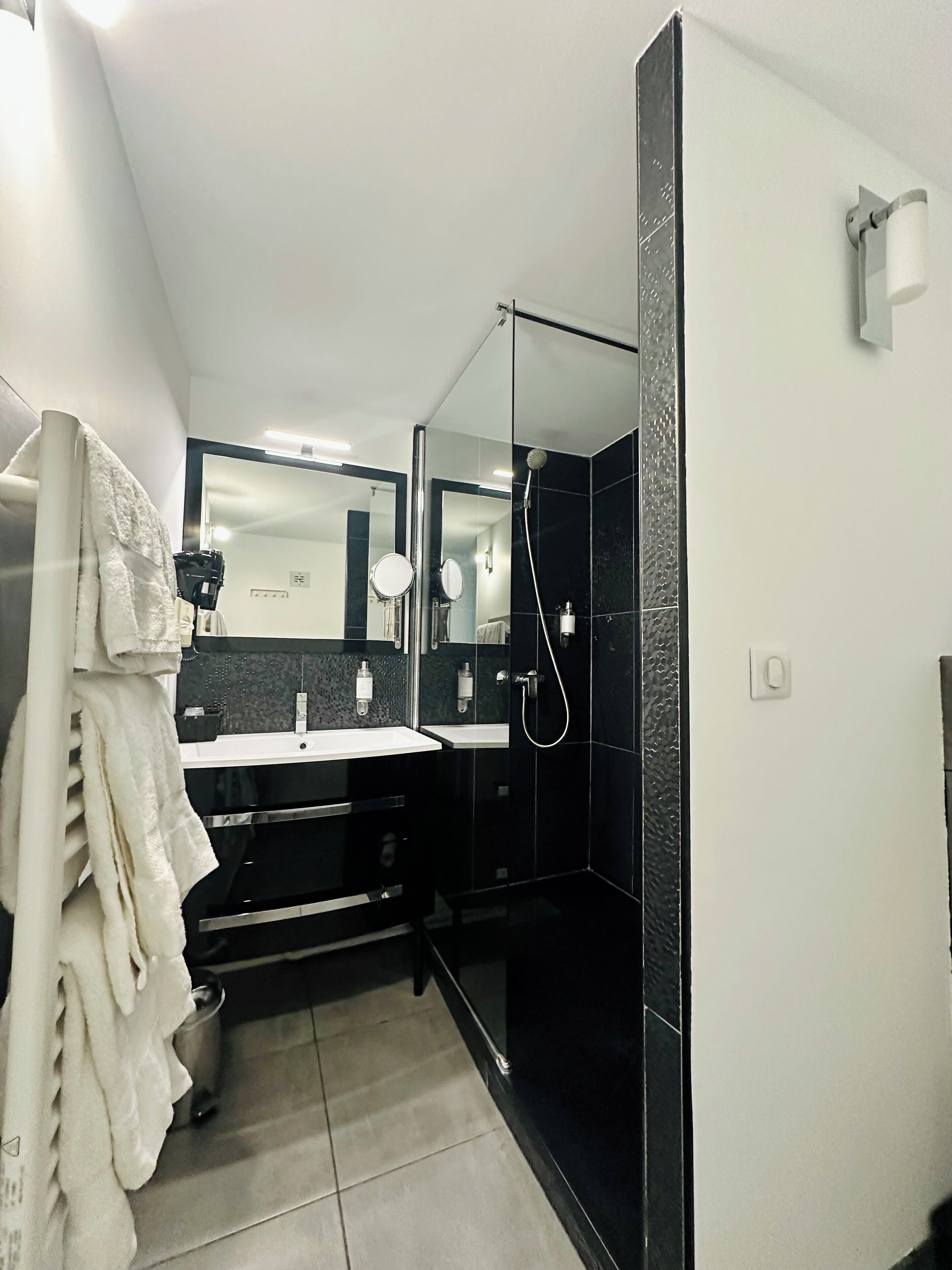 A modern bathroom with a black and white color scheme, featuring a sink, mirror, and shower area.